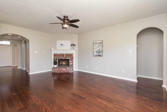 unfurnished living room featuring a fireplace, ceiling fan, dark hardwood / wood-style flooring, and a textured ceiling