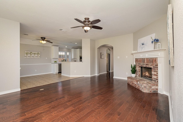 unfurnished living room with hardwood / wood-style floors, ceiling fan, and a brick fireplace