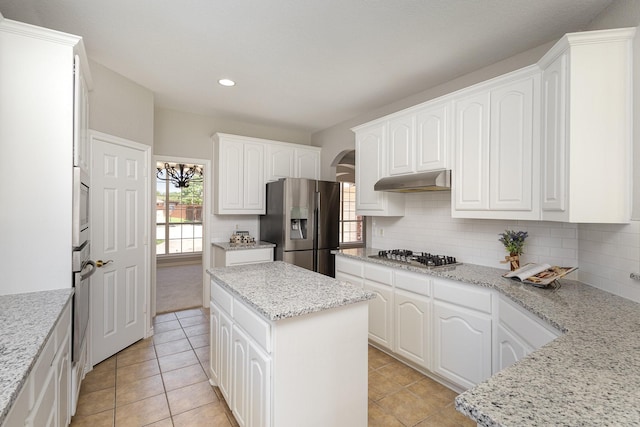 kitchen with stainless steel appliances, white cabinetry, and light stone counters