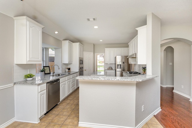 kitchen with tasteful backsplash, sink, white cabinets, and stainless steel appliances