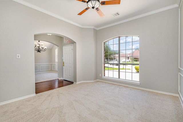 spare room featuring carpet flooring, ceiling fan with notable chandelier, and ornamental molding