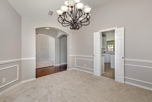 carpeted empty room with a chandelier