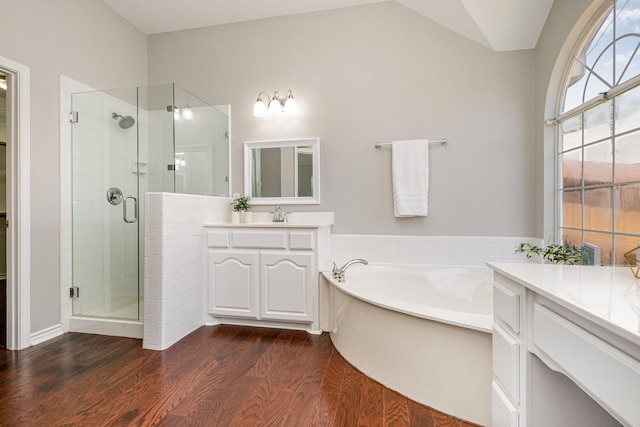 bathroom featuring vanity, wood-type flooring, plus walk in shower, and vaulted ceiling