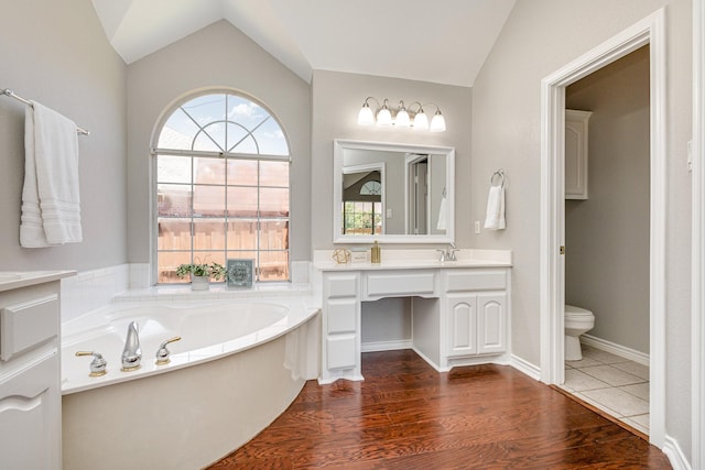 bathroom featuring a tub, hardwood / wood-style floors, vanity, and vaulted ceiling