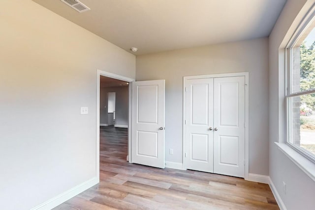 unfurnished bedroom featuring light wood-type flooring and a closet
