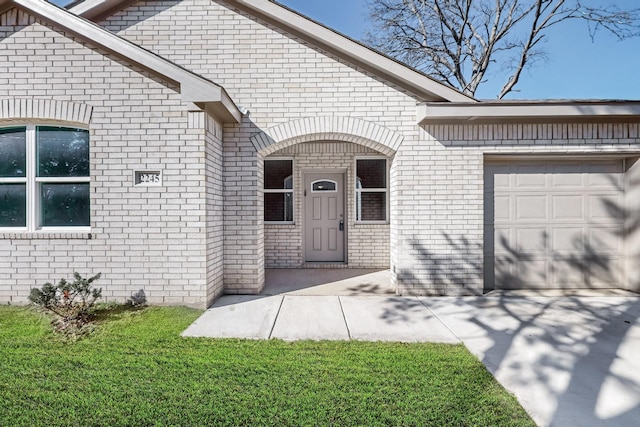 entrance to property with a garage and a lawn
