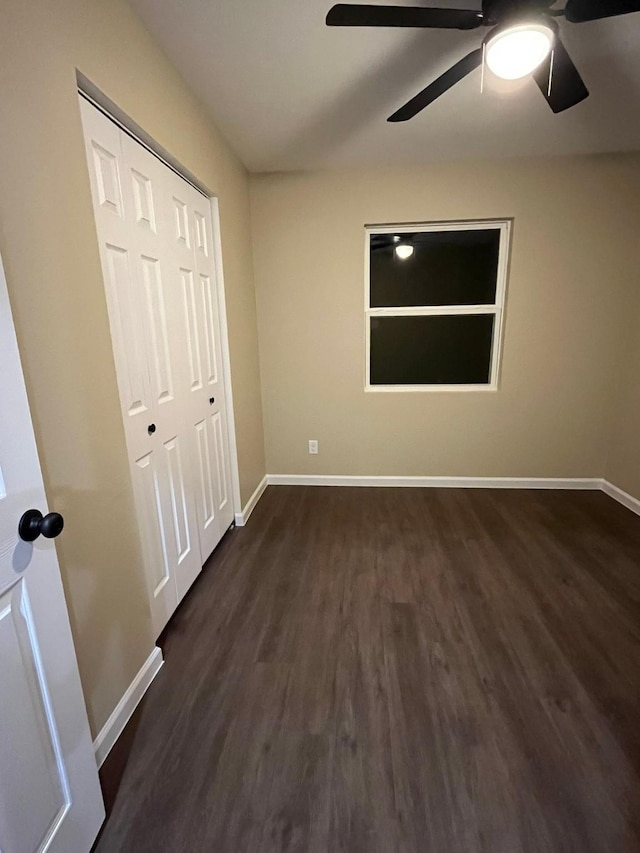 unfurnished bedroom with ceiling fan, dark wood-type flooring, and a closet