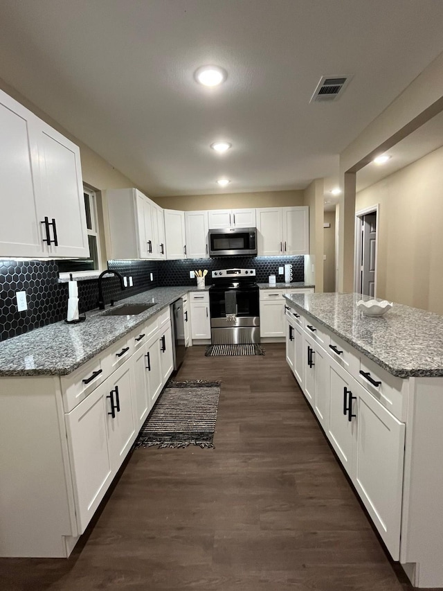 kitchen with white cabinets, sink, decorative backsplash, appliances with stainless steel finishes, and light stone counters