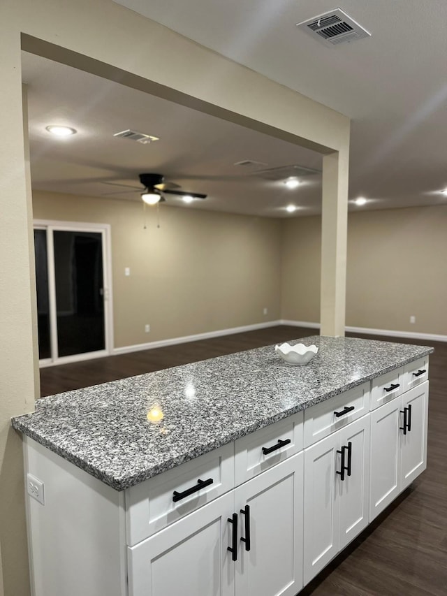 kitchen with white cabinetry, dark wood-type flooring, ceiling fan, and light stone counters