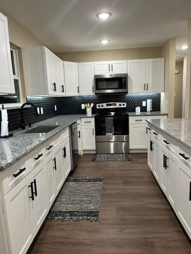 kitchen featuring sink, stainless steel appliances, light stone counters, dark hardwood / wood-style flooring, and white cabinets