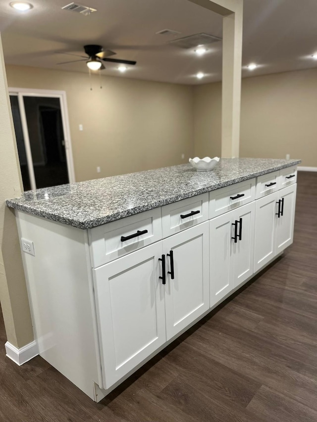 kitchen with white cabinets, light stone countertops, dark wood-type flooring, and ceiling fan