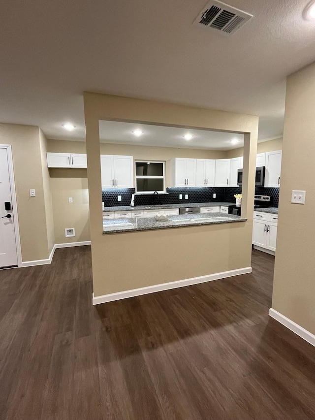 kitchen featuring white cabinetry, dark wood-type flooring, stainless steel appliances, and light stone counters