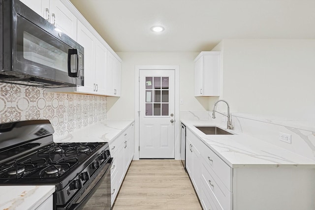 kitchen with white cabinets, sink, light stone countertops, and black appliances