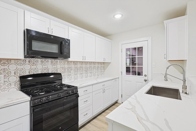 kitchen featuring white cabinetry, sink, tasteful backsplash, light stone counters, and black appliances