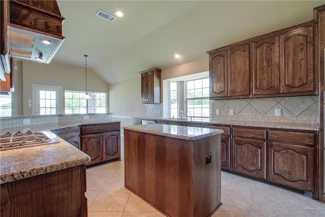 kitchen featuring lofted ceiling, stainless steel gas cooktop, a center island, a wealth of natural light, and decorative backsplash