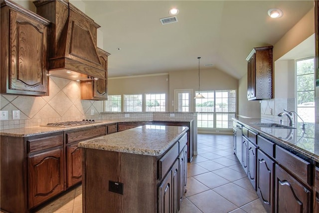 kitchen with stainless steel gas cooktop, sink, kitchen peninsula, a kitchen island, and decorative backsplash