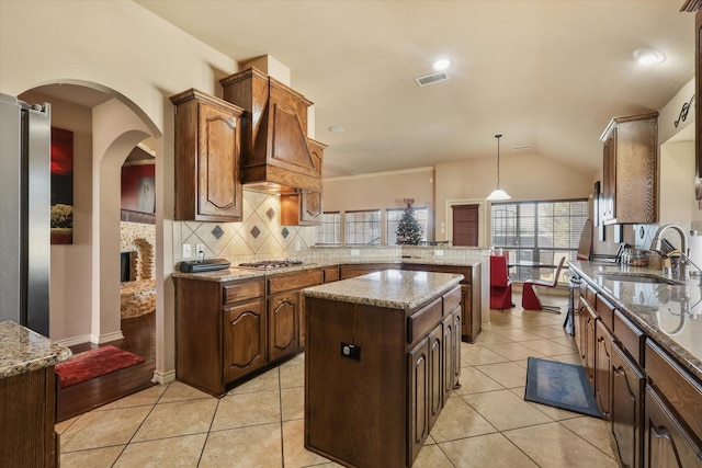 kitchen featuring a kitchen island, pendant lighting, tasteful backsplash, stainless steel gas stovetop, and sink