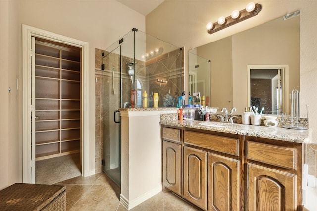 bathroom with tile patterned flooring, vanity, and walk in shower