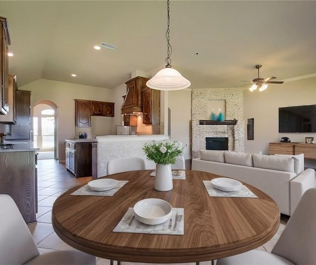 dining room with light tile patterned flooring, vaulted ceiling, ceiling fan, and a fireplace