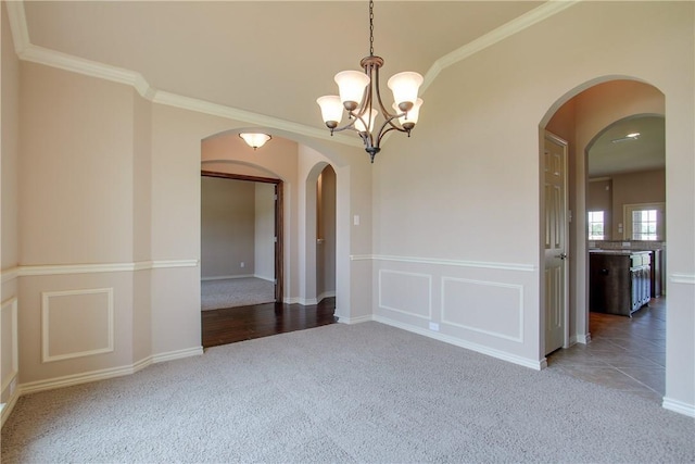 spare room with crown molding, carpet floors, and a notable chandelier