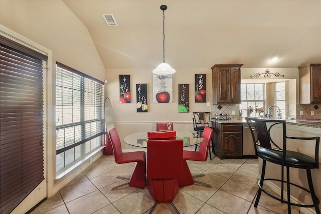 tiled dining area with lofted ceiling and sink