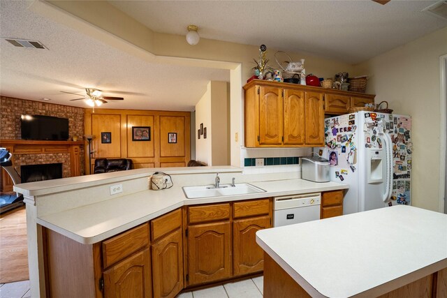 kitchen with white appliances, sink, light tile patterned floors, a textured ceiling, and a fireplace