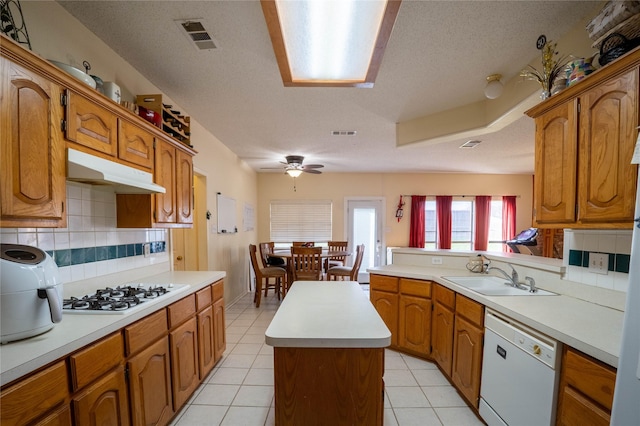 kitchen featuring white appliances, sink, tasteful backsplash, a kitchen island, and kitchen peninsula