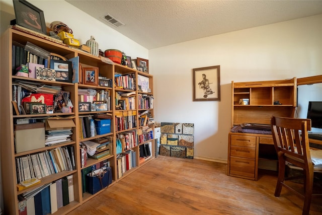 home office with wood-type flooring and a textured ceiling