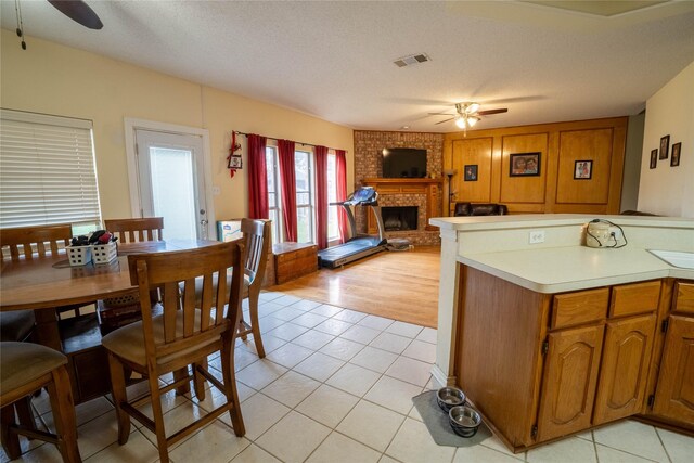 kitchen featuring a fireplace, light tile patterned floors, a textured ceiling, and ceiling fan