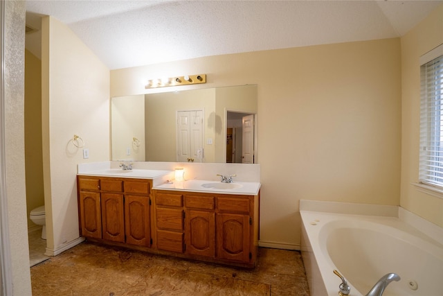 bathroom with a bath, a textured ceiling, vaulted ceiling, toilet, and vanity