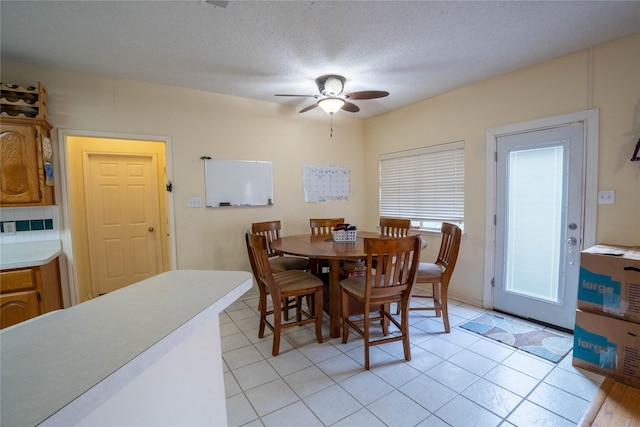 tiled dining area with ceiling fan and a textured ceiling