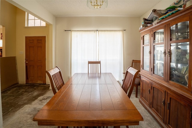 carpeted dining space with a notable chandelier and a textured ceiling