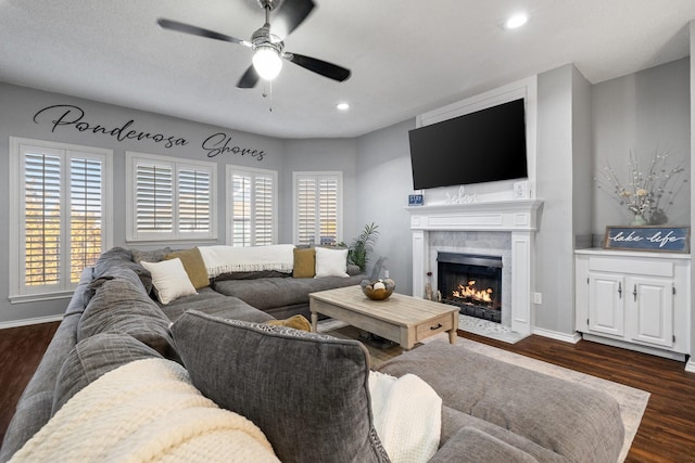 living room with dark hardwood / wood-style floors, ceiling fan, and a tiled fireplace