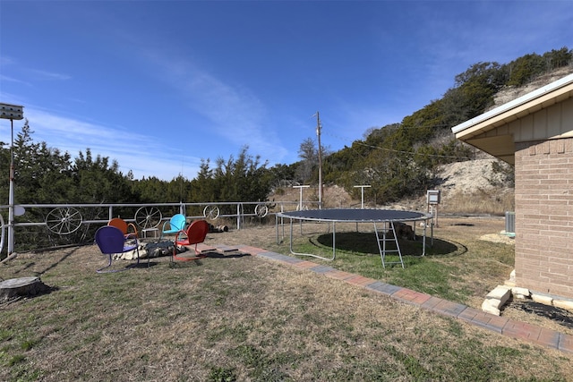 view of yard featuring a trampoline and an outdoor fire pit