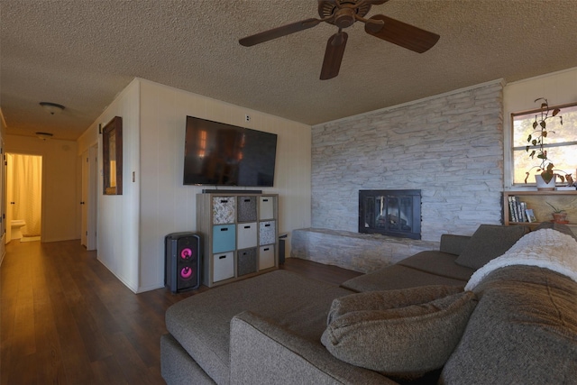 living room with hardwood / wood-style floors, a stone fireplace, and a textured ceiling