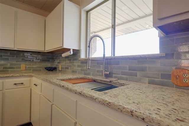 kitchen featuring tasteful backsplash, white cabinetry, sink, and a healthy amount of sunlight