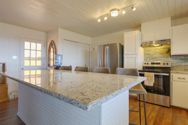 kitchen featuring appliances with stainless steel finishes, a kitchen breakfast bar, a center island, light stone countertops, and white cabinets