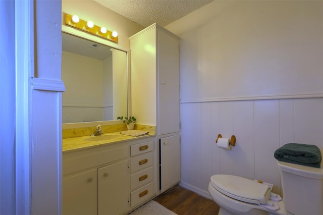 bathroom with wood-type flooring, toilet, a textured ceiling, and vanity