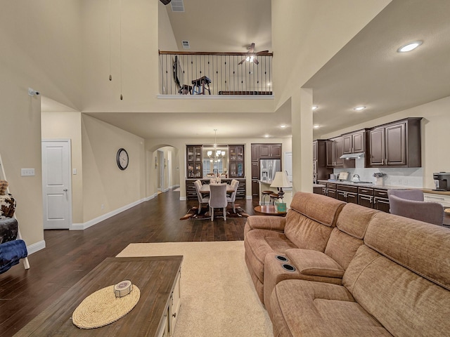 living room with dark hardwood / wood-style floors, ceiling fan, and a towering ceiling