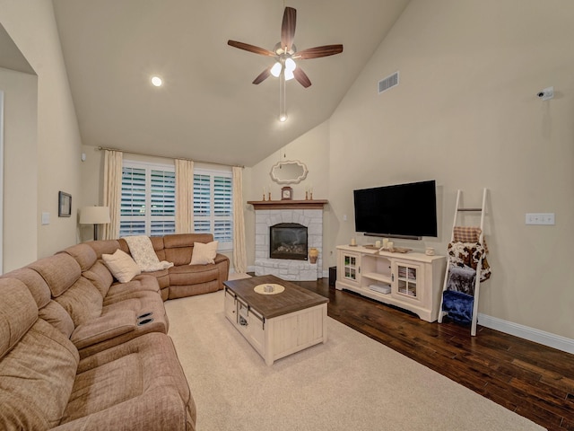 living room featuring ceiling fan, high vaulted ceiling, a stone fireplace, and hardwood / wood-style floors