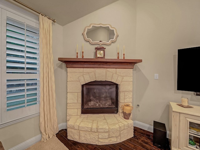 sitting room with a stone fireplace and dark wood-type flooring