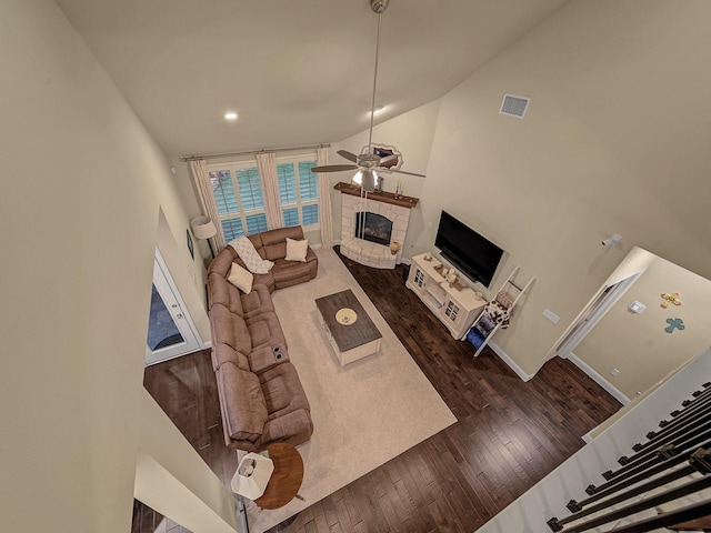 living room featuring dark wood-type flooring, a fireplace, high vaulted ceiling, and ceiling fan