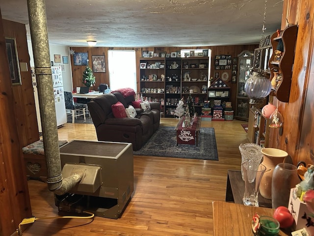 living room featuring wooden walls, wood-type flooring, and a textured ceiling