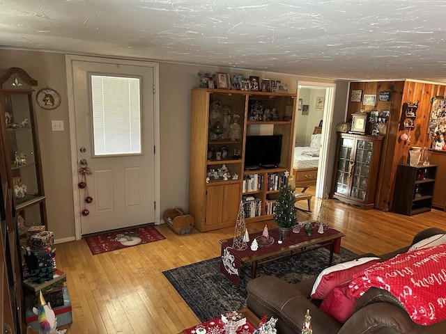 living room with wood walls, a textured ceiling, and light wood-type flooring