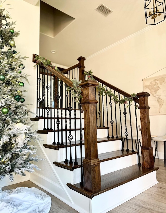 staircase featuring wood-type flooring and a notable chandelier