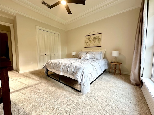 bedroom with crown molding, ceiling fan, a closet, and light colored carpet