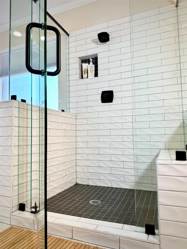 bathroom featuring tile patterned flooring, a shower with door, and ornamental molding