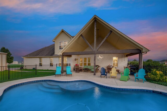 back house at dusk featuring a fenced in pool and a patio area