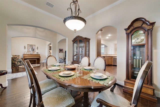 dining space with crown molding, dark hardwood / wood-style flooring, and sink