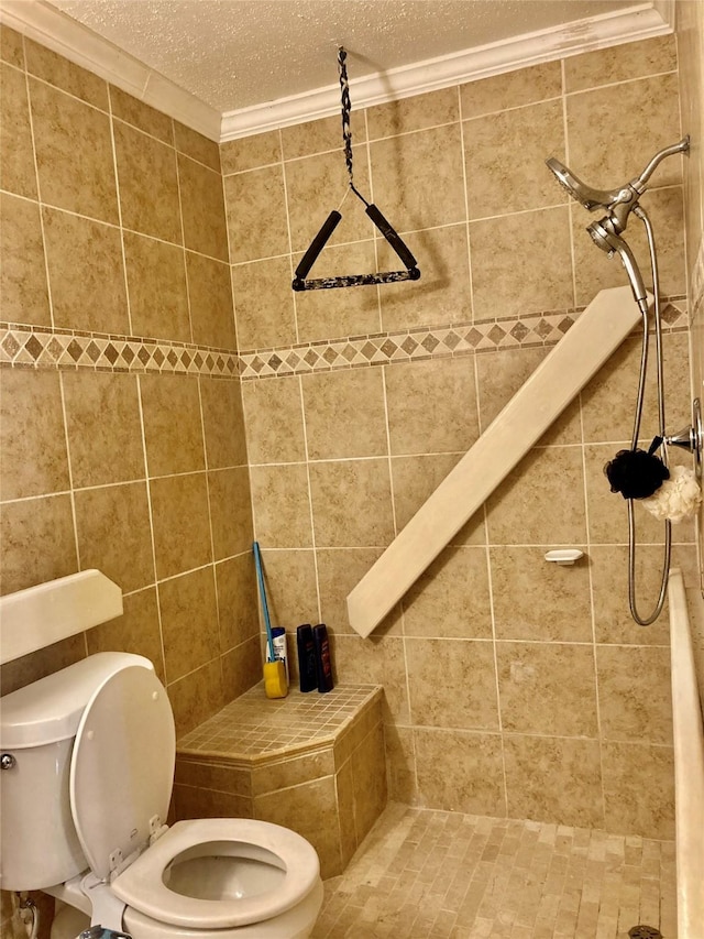 bathroom with a tile shower, ornamental molding, toilet, and a textured ceiling